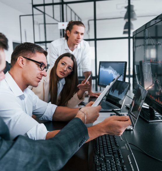 Analysing information. Team of stockbrokers works in modern office with many display screens Analysing information. Team of stockbrokers works in modern office with many display screens.