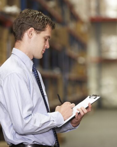 Manager In Warehouse With Clipboard