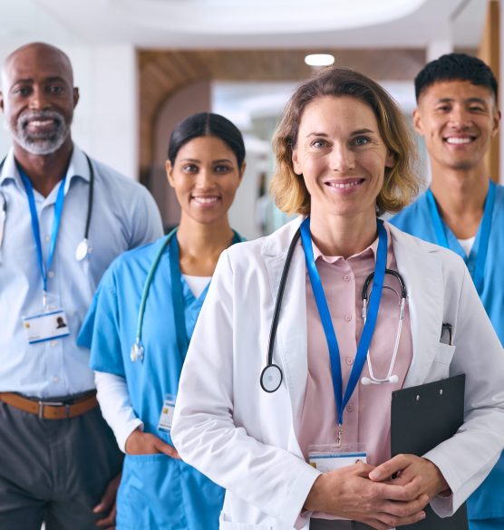 Portrait Of Smiling Multi Cultural Medical Team Wearing Scrubs And White Coats In Modern Hospital Portrait Of Smiling Multi Cultural Medical Team Wearing Scrubs And White Coats In Modern Hospital