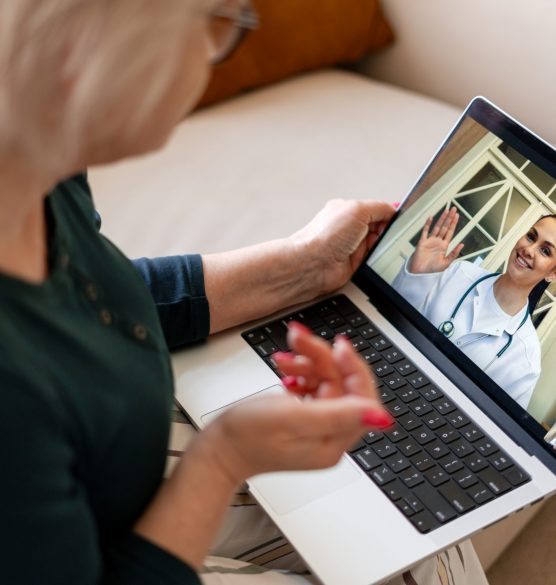 Senior woman having telemedicine video call with doctor Senior woman is using a laptop for an online consultation with a female doctor, receiving virtual healthcare at home